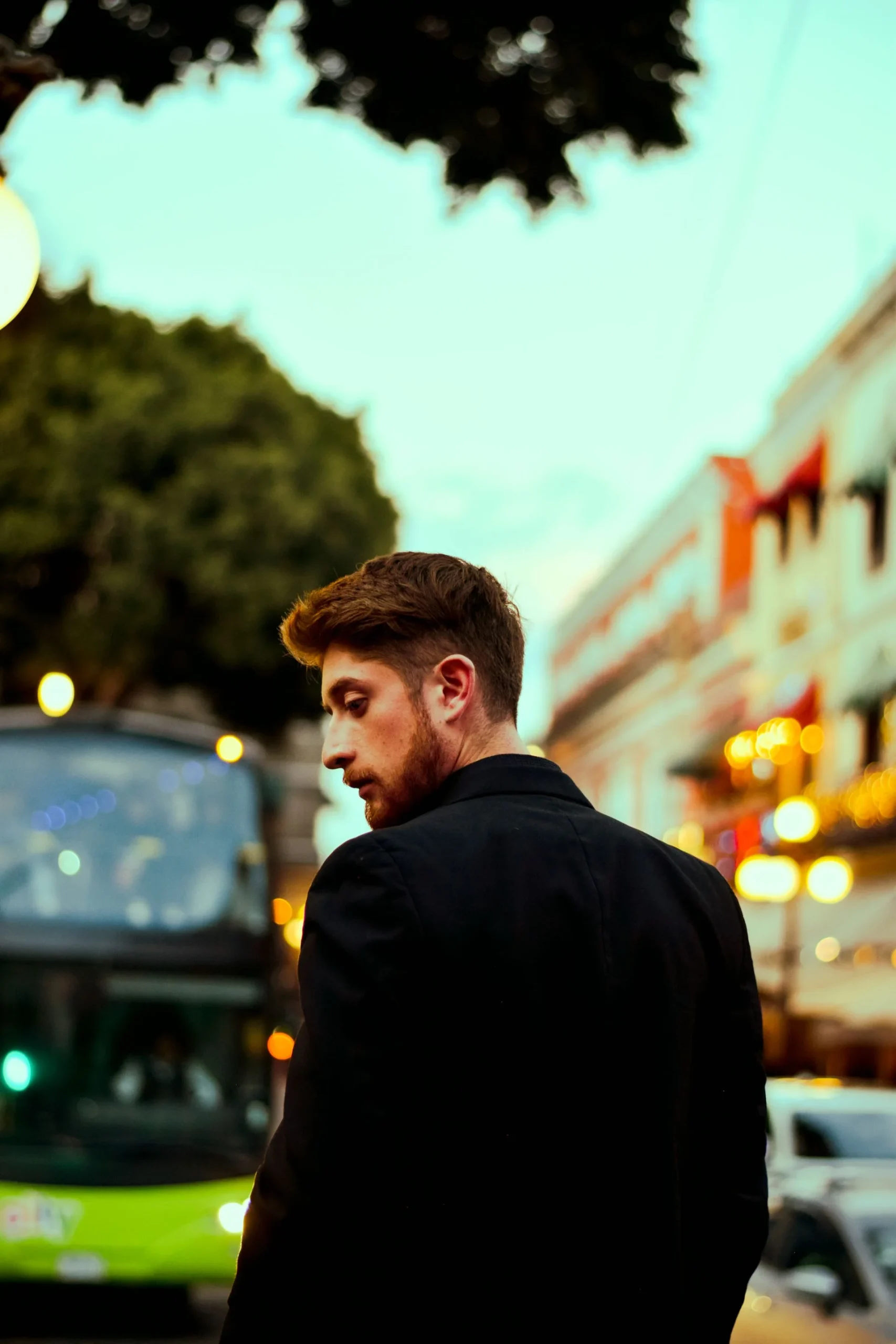 An adult walking along a softly lit city street at dusk