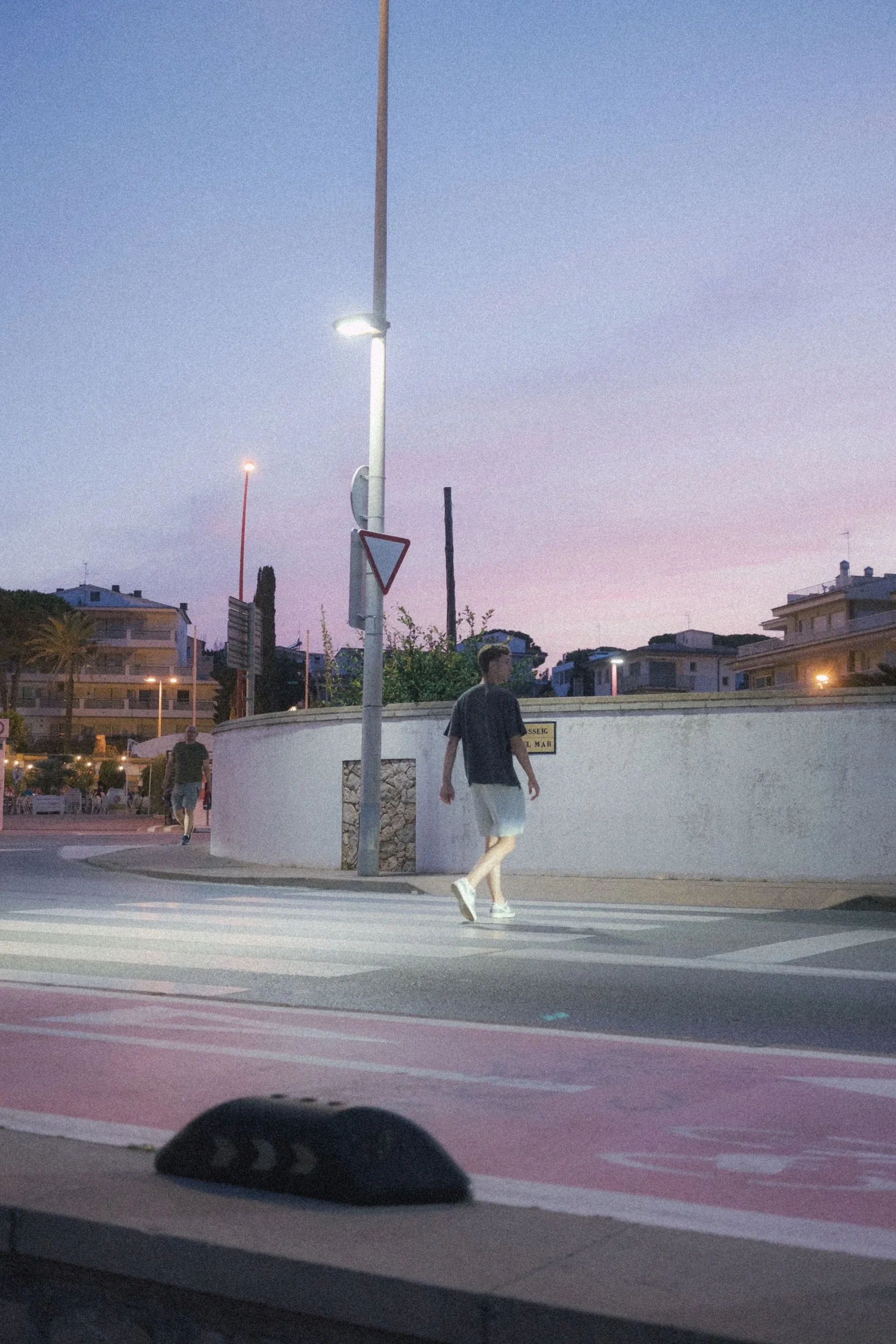 An adult walking along a quiet street in warm evening light
